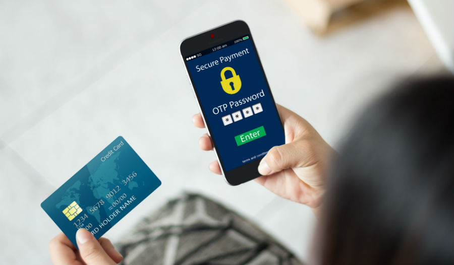 A person holding a credit / debit card in one hand and a mobile phone to make a secure payment in the other hand